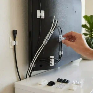 Multiple small adhesive clips tv cable management holding black cables neatly on a console.