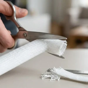A pair of scissors cuts a TV Kabelschutz Schlauch to the desired length.